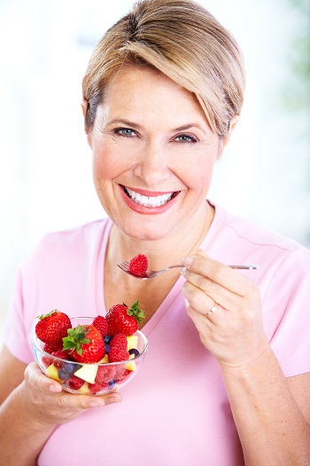 A senior woman enjoys food good for her teeth.