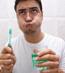 A man uses mouthwash after brushing his teeth.