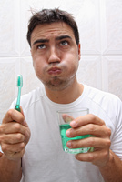 A man uses mouthwash after brushing his teeth.